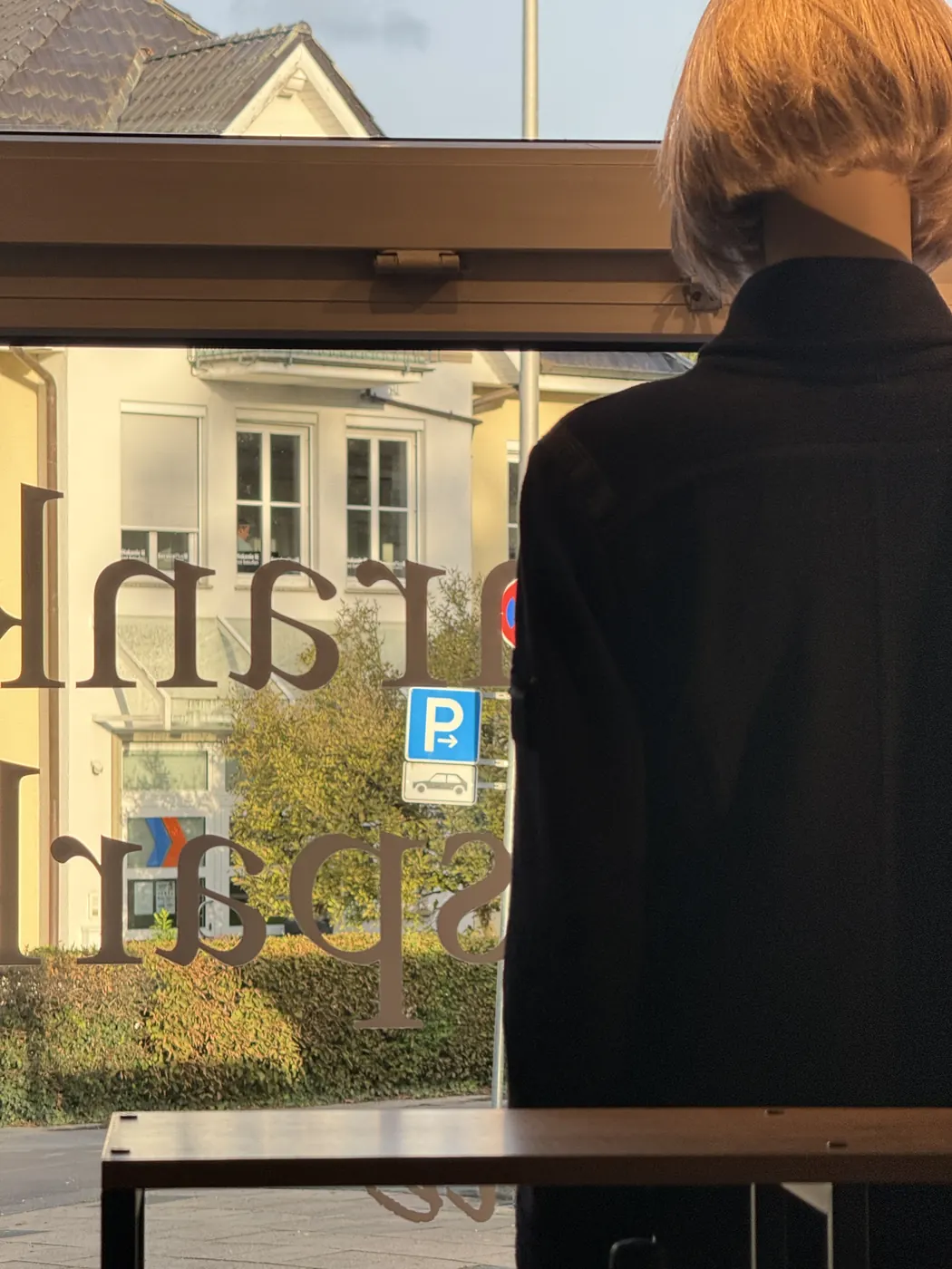 Blick aus dem Schaufenster auf das Parkplatzschild gegenüber